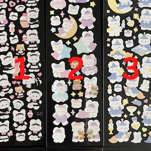 May include: Three sheets of stickers featuring cute cartoon bears in various poses and outfits. The first sheet features bears in maid outfits, the second sheet features bears in pajamas, and the third sheet features bears in wizard costumes. Each sheet has a black background and includes stars, moons, and other decorative elements.