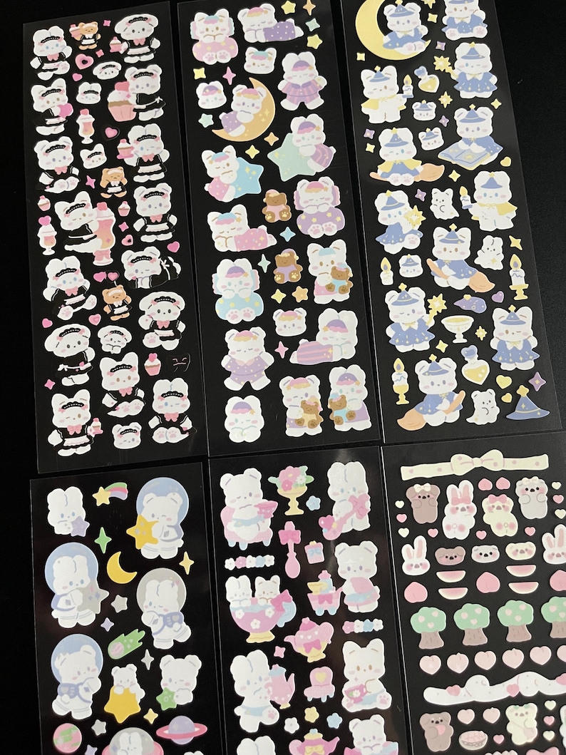 May include: Six sheets of stickers featuring adorable cartoon bears in various poses and outfits. The stickers are on a black background and include stars, moons, and other decorative elements.