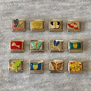 Puede incluir: Doce pulseras de charms coloridos con varios diseños, incluyendo una mariposa, una piña, una libélula, una llave, una fresa, una cabeza de Mickey Mouse, una flor, una ola, un sombrero, un hada y un patrón de vitral.