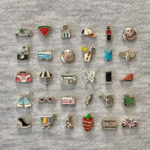 May include: A collection of silver charms with colorful enamel details. The charms include a scooter, watermelon slice, purse, umbrella, sunglasses, a pink van, a sneaker, a shopping cart, a strawberry, and more.