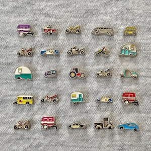 May include: A collection of miniature vehicle charms, including cars, motorcycles, trailers, and buses. The charms are in various colors, such as red, yellow, blue, and silver, and are set against a gray background.