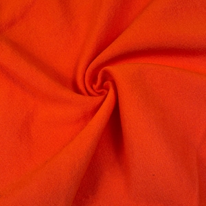 May include: Close-up of a vibrant orange fabric with a textured surface. The material is gathered and swirled, creating a dynamic pattern of folds and shadows. The bright color suggests a textile suitable for clothing or home decor.