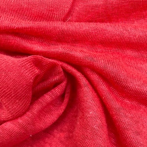 May include: Close-up of a red knitted fabric with a textured surface.