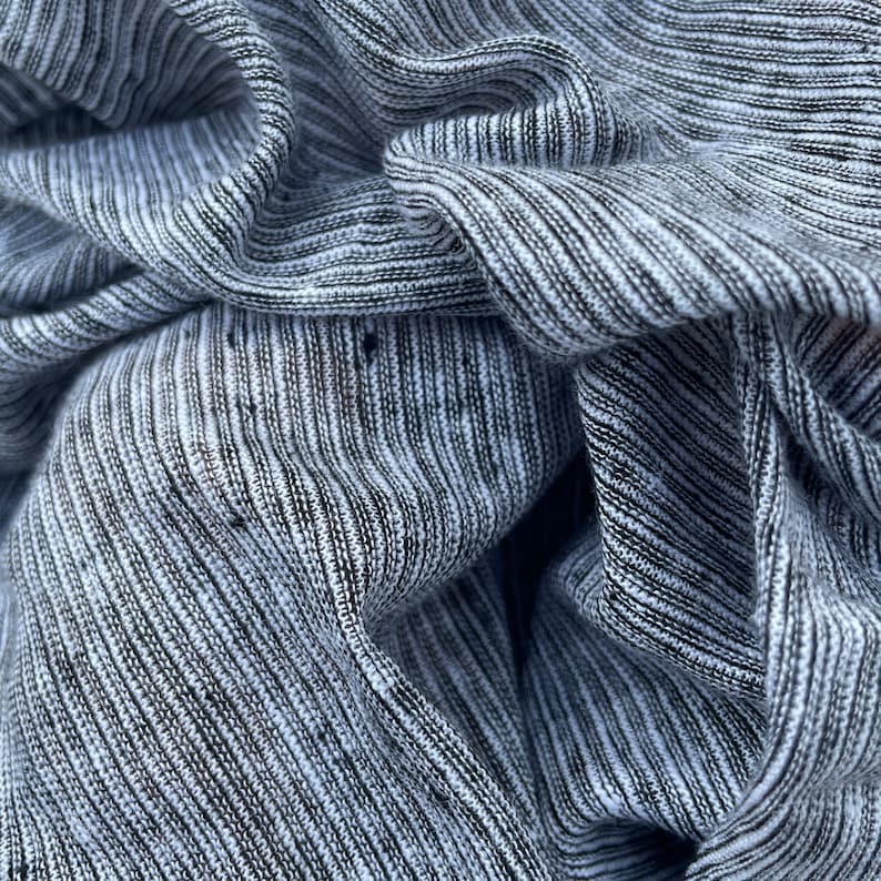 May include: Close-up of a gray and white striped fabric with a textured, ribbed surface.