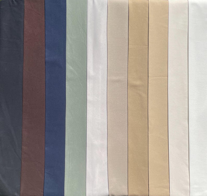 May include: A collection of fabric swatches in various shades of blue, green, beige, and white. The swatches are arranged in a vertical row, with the darkest shade at the left and the lightest shade at the right.