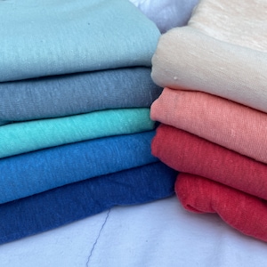 May include: A stack of fabric in various shades of blue, teal, red, pink, and white. The fabric is soft and textured, perfect for crafting or sewing projects.
