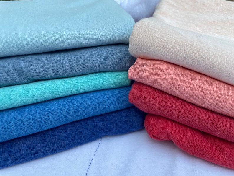 May include: A stack of fabric in various shades of blue, teal, red, pink, and white. The fabric is soft and textured, perfect for crafting or sewing projects.