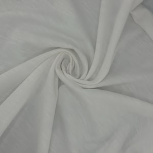 Puede incluir: Primer plano de tela blanca, fuertemente arremolinada en el centro. La tela tiene una textura sutil y parece ligera. Los pliegues crean sombras y reflejos, a&ntilde;adiendo profundidad a la imagen. La impresi&oacute;n general es de suavidad y ca&iacute;da.