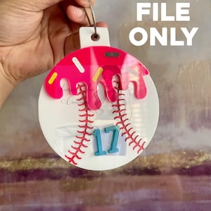 May include: A baseball-themed ornament with a pink glazed donut design. The ornament features a baseball stitch pattern, the number 17 in blue, and the text "SVG FILE ONLY". The ornament is held by a string.