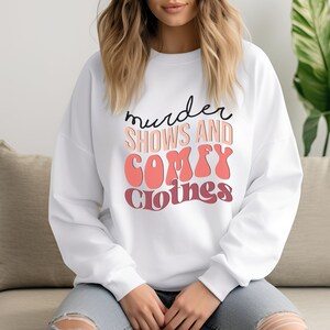 May include: White sweatshirt with the text "murder shows and comfy clothes" in black and pink lettering.