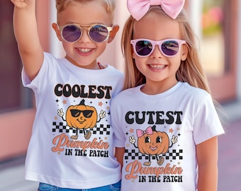 May include: Two children wearing white t-shirts with a pumpkin graphic and the text "Coolest Pumpkin in the Patch" and "Cutest Pumpkin in the Patch".