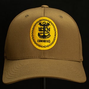 May include: A brown baseball cap with a yellow and black embroidered patch that says "USN COMMAND".