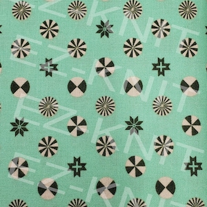 May include: A teal fabric with a repeating pattern of black and white geometric shapes. The shapes include circles with a radiating design and circles with a divided design.