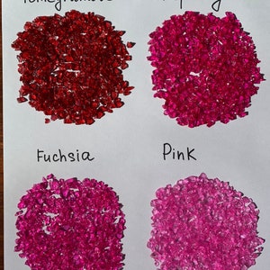 May include: Four piles of red, pink, and fuchsia colored glass pieces labeled "Pomegranate", "Raspberry", "Fuchsia", and "Pink".