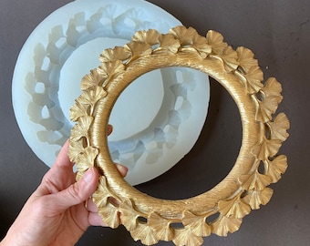 May include: A gold-colored metal wreath mold with a detailed ginkgo leaf design. The mold is made of silicone and is shown next to a finished wreath.