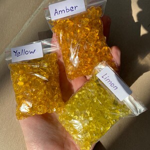 May include: Three small bags of glass beads in different shades of yellow. The bags are labelled "Amber", "Yellow", and "Limon".