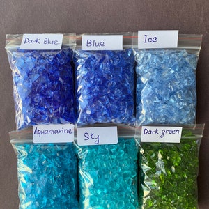 May include: Six bags of crushed glass, each labeled with a color name: Dark Blue, Blue, Ice, Aquamarine, Sky, and Dark Green.