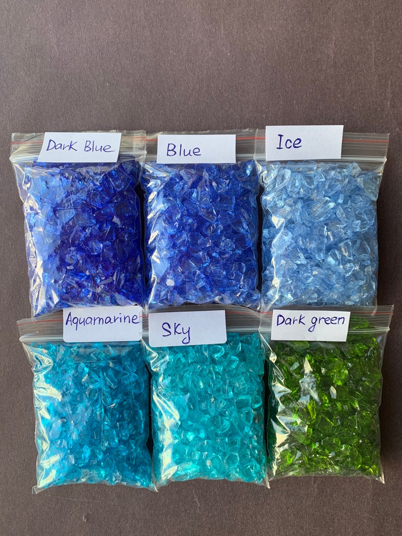 May include: Six bags of crushed glass, each labeled with a color name: Dark Blue, Blue, Ice, Aquamarine, Sky, and Dark Green.
