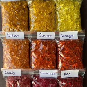May include: Nine bags of crushed glass, each labelled with a colour name. The colours are: Amber, Yellow, Limon, Apricot, Sunset, Orange, Candy, Watermelon, and Red.