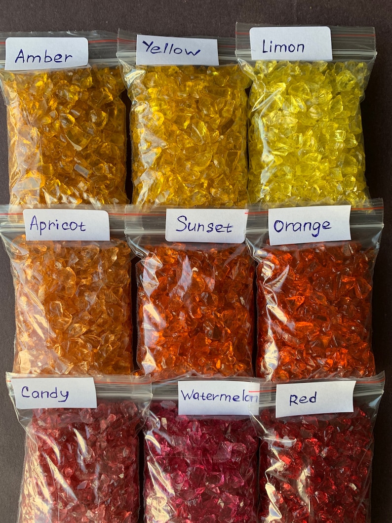 May include: Nine bags of crushed glass, each labelled with a colour name. The colours are: Amber, Yellow, Limon, Apricot, Sunset, Orange, Candy, Watermelon, and Red.