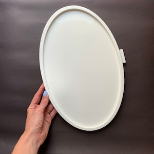 May include: White oval tray with a raised edge. The tray is made of a smooth, hard material and is ideal for serving snacks or drinks.