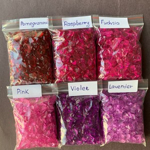 May include: Six clear plastic bags filled with crushed glass, each bag labeled with a color name: Pomegranate, Raspberry, Fuchsia, Pink, Violet, and Lavender.
