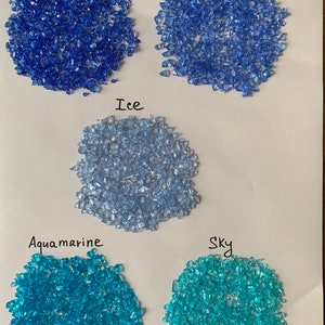 May include: Five samples of crushed glass in different shades of blue and turquoise. The colors are labeled "Dark Blue", "Blue", "Ice", "Aquamarine", and "Sky".