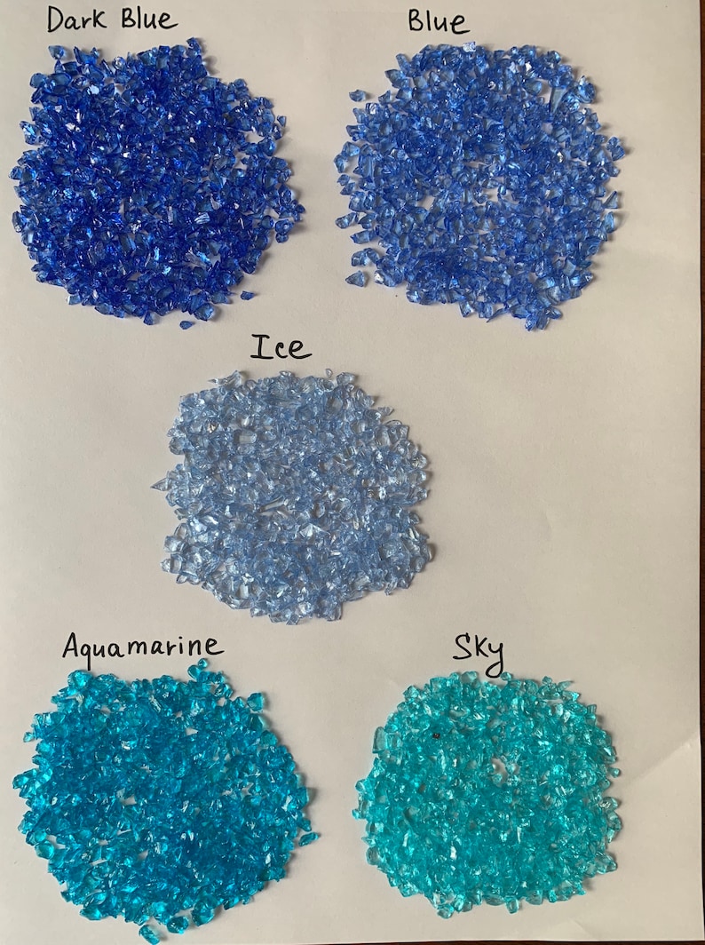 May include: Five samples of crushed glass in different shades of blue and turquoise. The colors are labeled "Dark Blue", "Blue", "Ice", "Aquamarine", and "Sky".
