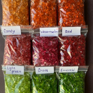 May include: Nine bags of crushed glass, each labelled with a colour name. The colours are: Apricot, Sunset, Orange, Candy, Watermelon, Red, Light Green, Grass, and Emerald.