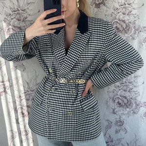 May include: A black and white gingham blazer with a black collar and a gold chain belt. The blazer is double-breasted and has a relaxed fit.