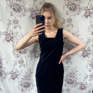 Pu&ograve; includere: Un abito in velluto blu navy senza maniche con scollo quadrato. L'abito &egrave; aderente e ha una lunghezza corta.