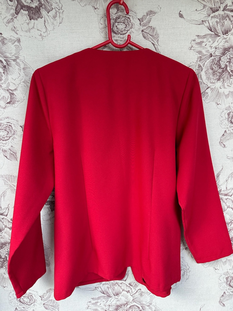 Puede incluir: Una chaqueta roja de manga larga con cuello en V.