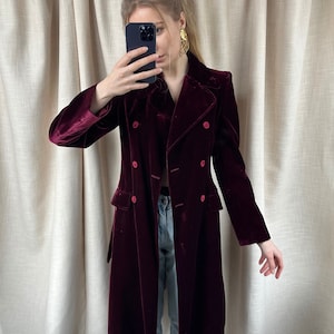 May include: A long, burgundy velvet coat with a double-breasted closure and a classic collar.