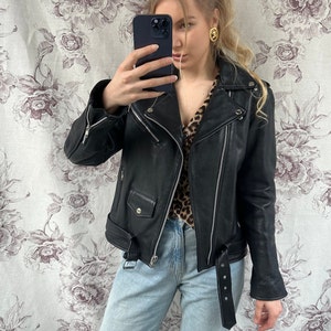 May include: A black leather motorcycle jacket with a zipper closure and a belt at the waist.
