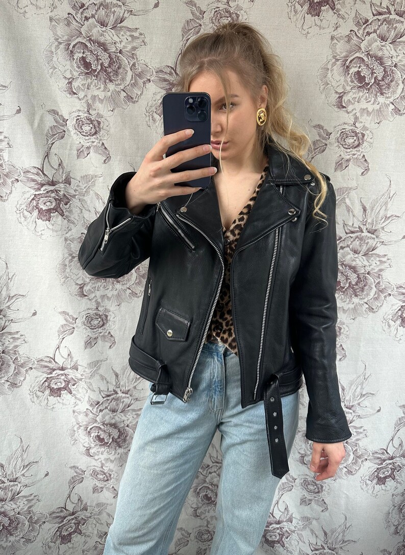 May include: A black leather motorcycle jacket with a zipper closure and a belt at the waist.