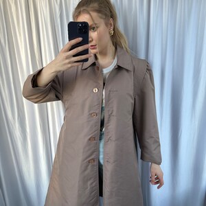 May include: A long-sleeved, brown, collared jacket with a button-up front. The jacket has a slightly fitted silhouette and features a subtle texture.