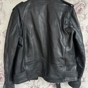 May include: Black leather motorcycle jacket with a zipper closure and a belt at the waist.