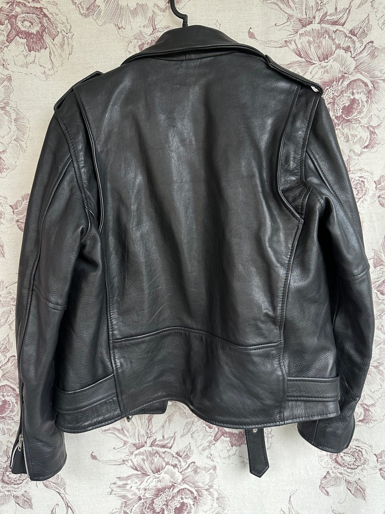 May include: Black leather motorcycle jacket with a zipper closure and a belt at the waist.