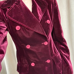 May include: A long, burgundy velvet coat with a double-breasted closure and four large buttons.