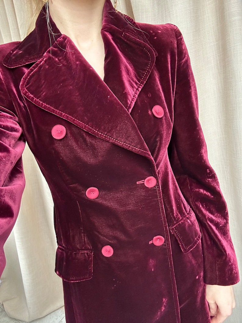 May include: A long, burgundy velvet coat with a double-breasted closure and four large buttons.