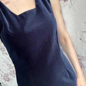 Pu&ograve; includere: Un abito senza maniche in velluto blu scuro con scollo quadrato.