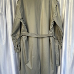 May include: A long, light gray trench coat with a belt and a single back seam. The coat has a collar and long sleeves.