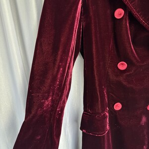 May include: A long, burgundy velvet coat with a double-breasted closure and large buttons.