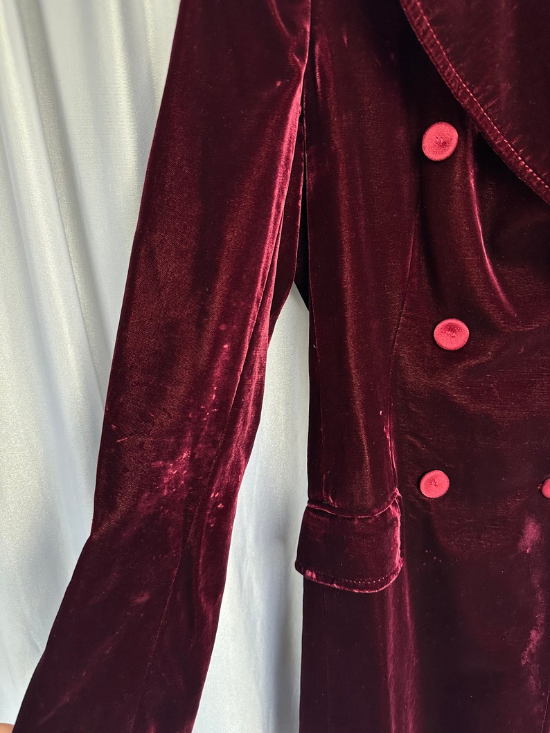 May include: A long, burgundy velvet coat with a double-breasted closure and large buttons.
