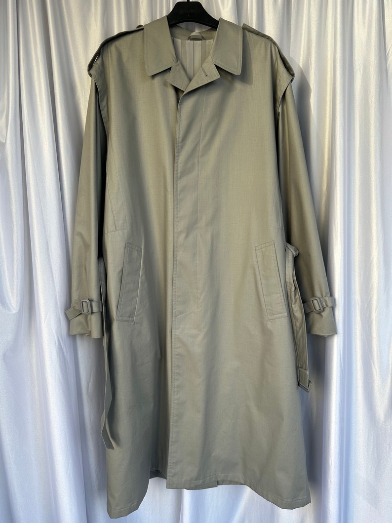 May include: A long, light green trench coat with a belt and buckle closures on the sleeves.