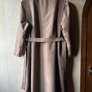 May include: A long brown coat with a belt and decorative stitching on the sleeves.