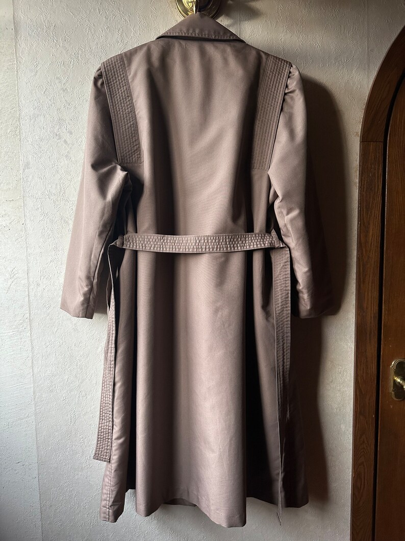 May include: A long brown coat with a belt and decorative stitching on the sleeves.
