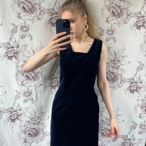 Pu&ograve; includere: Un abito in velluto blu navy senza maniche con scollo quadrato.