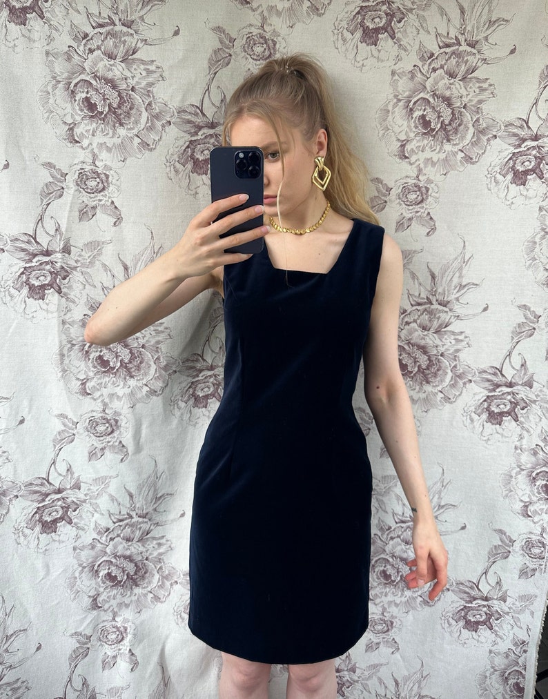 Pu&ograve; includere: Un abito in velluto blu navy senza maniche con scollo quadrato.