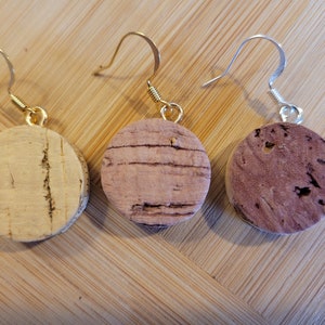 May include: Three pairs of cork earrings with gold and silver hooks. The cork is natural and has a light brown color.
